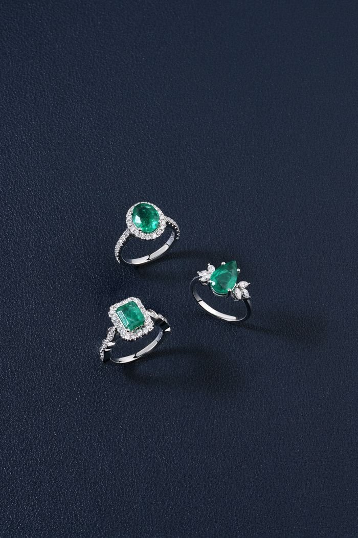 Showcasing three exquisite emerald and diamond rings against a dark backdrop, perfect for jewelry enthusiasts.